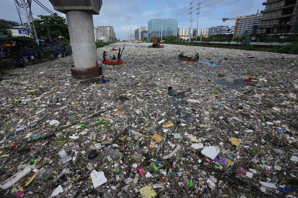 Workers try to clear a sea of garbage and debris brought by intense monsoon rains at the Redemptorist Water Channel in Paranaque city, Metro Manila, Philippines on Tuesday, Aug. 11, 2026. (AP Photo/Aaron Favila)