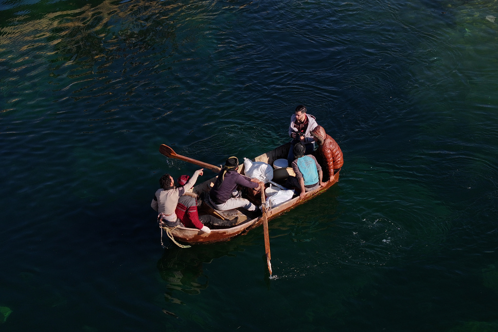FILE - Displaced Syrians cross a river in a boat near the village of Rasm al-Harmil al-Imam in the eastern Aleppo countryside, near the front line with the Kurdish-led Syrian Democratic Forces, in Deir Hafer, Syria, Friday, Jan. 16, 2026. (AP Photo/Ghaith Alsayed)