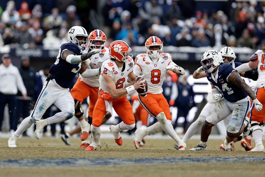 Clemson quarterback Cade Klubnik (2) runs away from Penn State defensive end Dani Dennis-Sutton (33) during the second half of the Pinstripe Bowl NCAA college football game at Yankee Stadium Saturday, Dec. 27, 2025, in New York. (AP Photo/Adam Hunger)