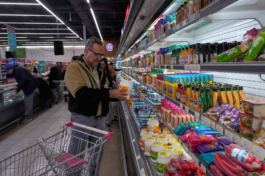 A man checks information on a yogurt's package at a store in Tehran, Iran, Friday, Jan. 16, 2026. (AP Photo/Vahid Salemi)
