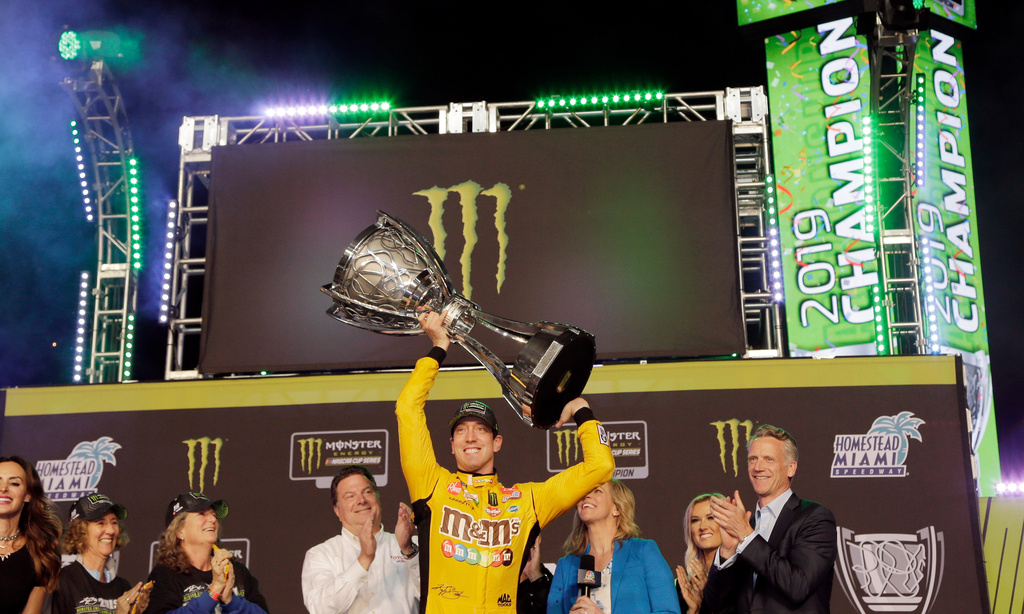 FILE - In this Nov. 17, 2019, file photo, Kyle Busch, center, holds up the trophy in Victory Lane after winning a NASCAR Cup Series auto racing season championship at Homestead-Miami Speedway in Homestead, Fla. (AP Photo/Terry Renna, File)