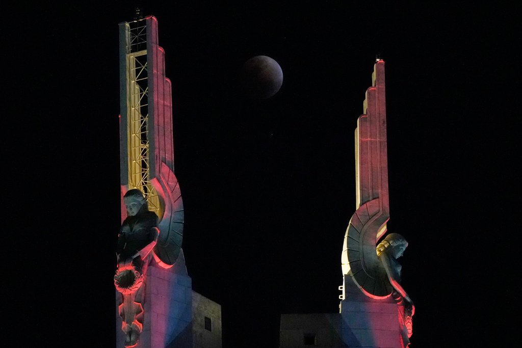 A total lunar eclipse is seen through statues at the Quezon Memorial Shrine in Quezon City, Philippines, Tuesday, March 3, 2026. (AP Photo/Aaron Favila)