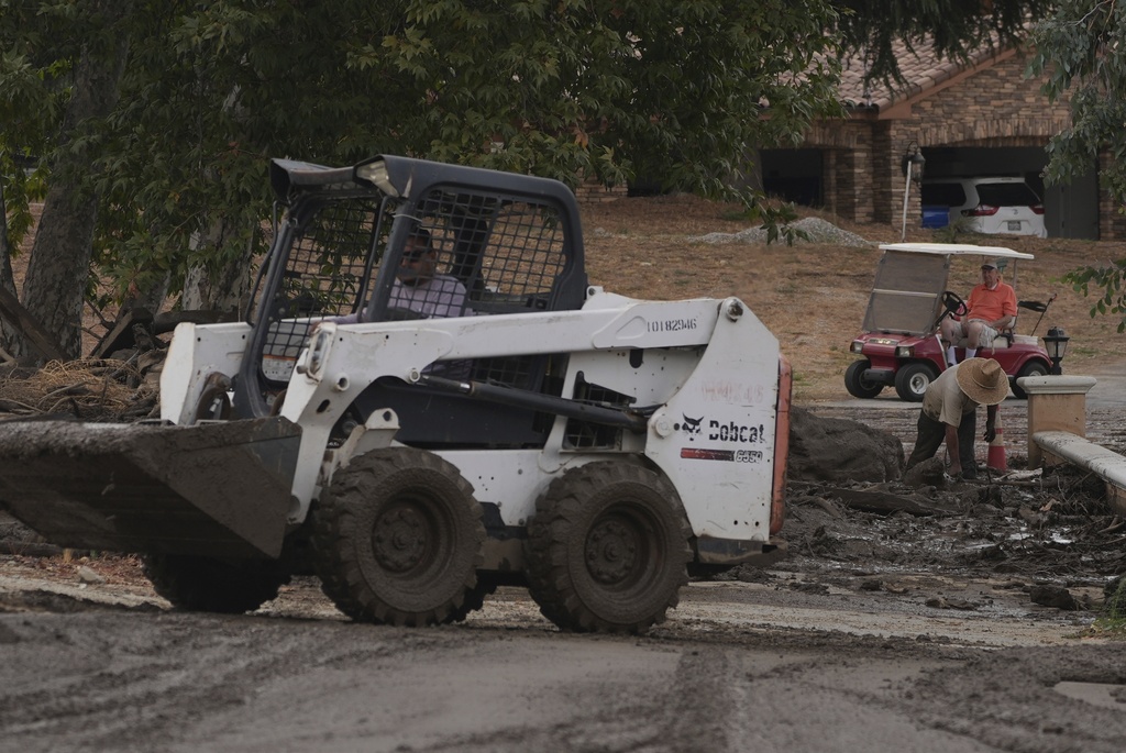 Workers and residents clean up the damage caused by mudslides after storms in Yucaipa, Calif., Friday, Sept. 19, 2025. (AP Photo/Damian Dovarganes)
