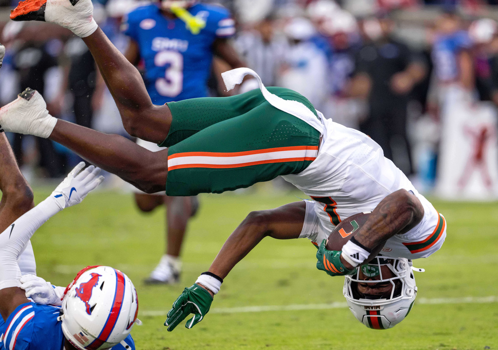 Miami wide receiver Joshisa Trader flips over SMU cornerback Marcellus Barnes Jr. into the end zone on a touchdown reception during the first half of an NCAA college football game, Saturday, Nov. 1, 2025, in Dallas. (AP Photo/Jeffrey McWhorter)
