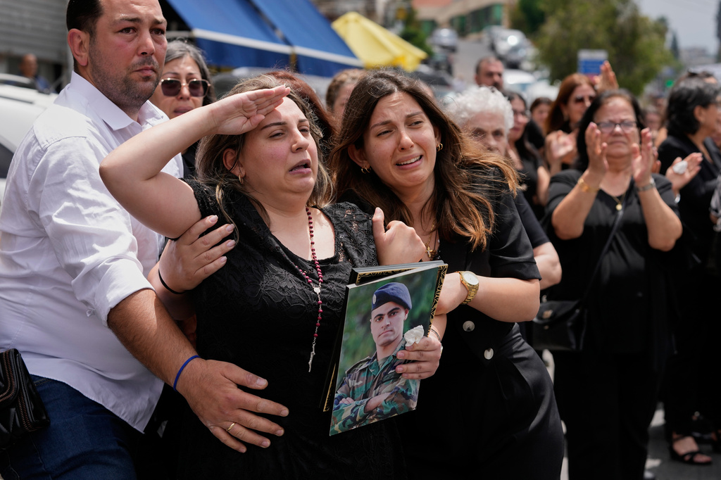 Rozette, second left, the wife of Lebanese army captain Elie Khoury, who was killed on Saturday in an Israeli airstrike, salutes during his funeral procession in Kfar Jarra, southern Lebanon, Monday, June 8, 2026. (AP Photo/Mohammed Zaatari)