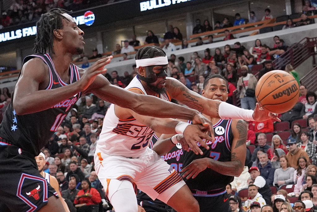 Phoenix Suns guard Jordan Goodwin, center, battles for a rebound against Chicago Bulls forward Leonard Miller, left, and guard Rob Dillingham during the first half of an NBA basketball game in Chicago, Sunday, April 5, 2026. (AP Photo/Nam Y. Huh)