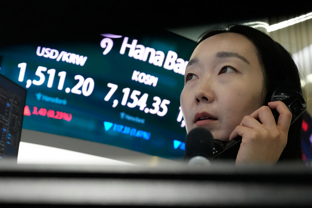 A currency trader talks on the phone near a screen showing the Korea Composite Stock Price Index (KOSPI) and the foreign exchange rate between U.S. dollar and South Korean won, left, at the foreign exchange dealing room of the Hana Bank headquarters in Seoul, South Korea, Wednesday, May 20, 2026. (AP Photo/Ahn Young-joon)