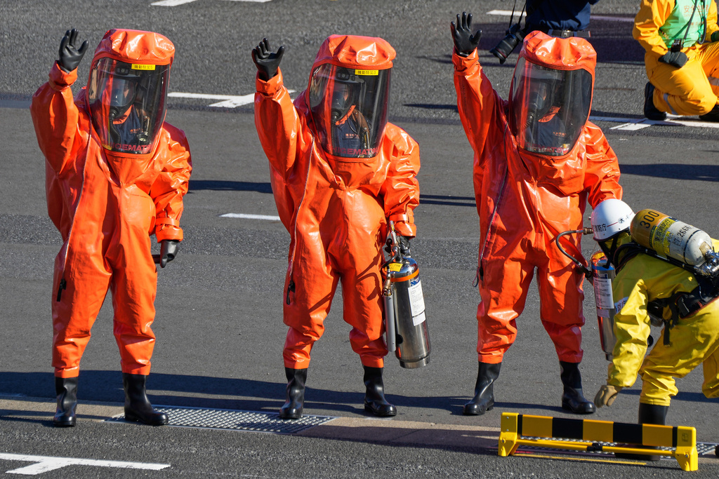 Members of firefighters with full-body hazardous materials protective suits, raise arms during the annual New Year's Fire Brigade Review Tuesday, Jan. 6, 2026, in Tokyo. (AP Photo/Eugene Hoshiko)