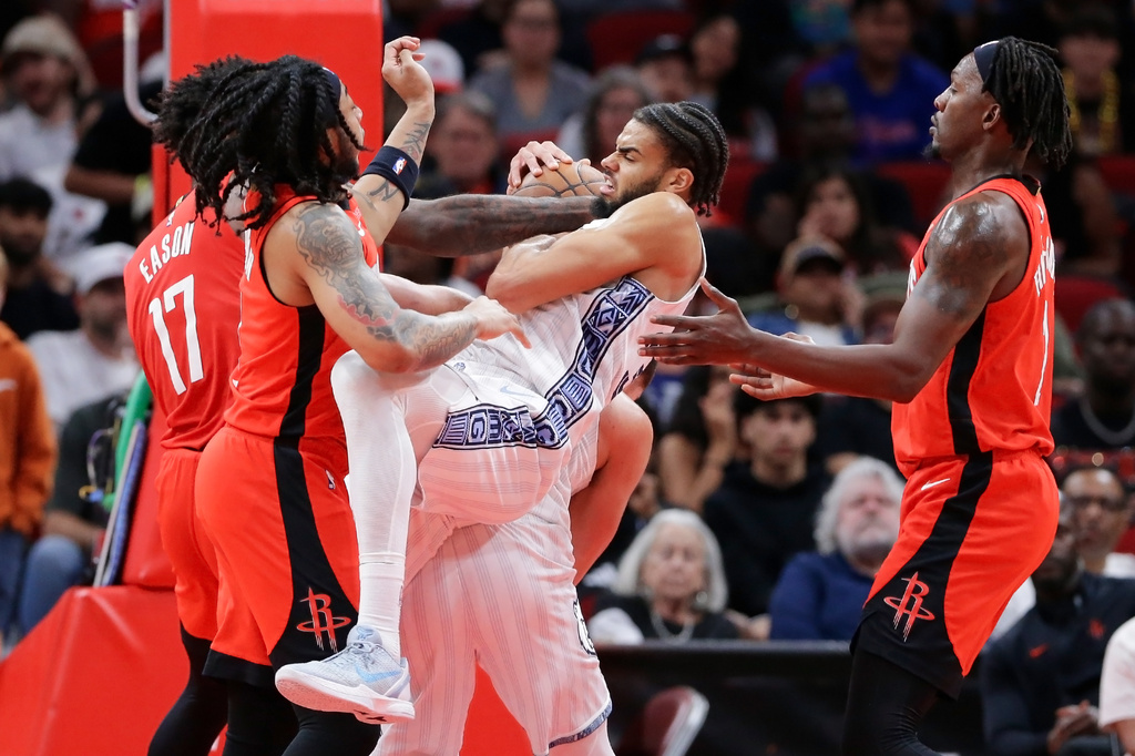 Memphis Grizzlies guard Rayan Rupert, center with ball, battles to keep a rebound between Houston Rockets forward Tari Eason, guard JD Davison, left, and forward Dorian Finney-Smith, right, during the first half of an NBA basketball game Sunday, April 12, 2026, in Houston. (AP Photo/Michael Wyke)