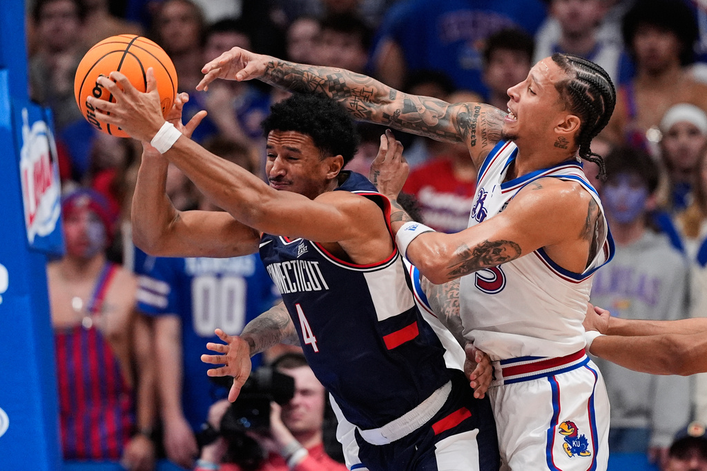 Kansas guard Tre White, right, tries to steal the ball from UConn forward Dwayne Koroma (4) during the first half of an NCAA college basketball game Tuesday, Dec. 2, 2025, in Lawrence, Kan. (AP Photo/Charlie Riedel)
