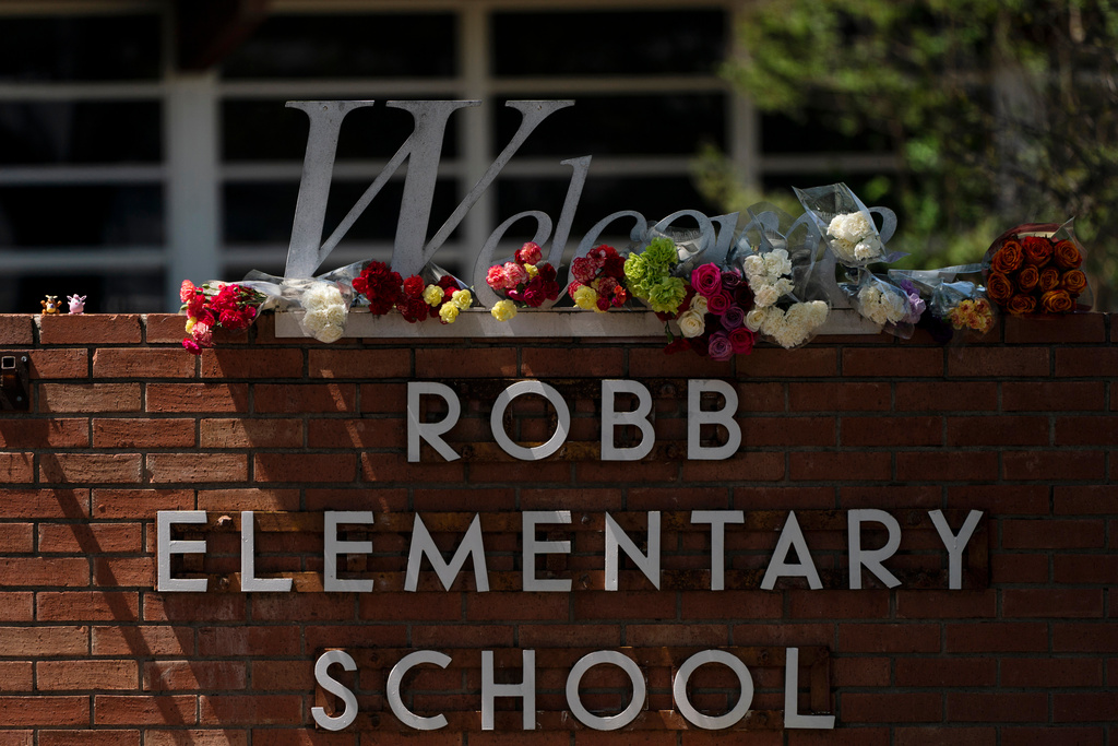 FILE - Flowers are placed around a welcome sign outside Robb Elementary School in Uvalde, Texas, May 25, 2022, to honor the victims killed in a shooting at the school. (AP Photo/Jae C. Hong, File)