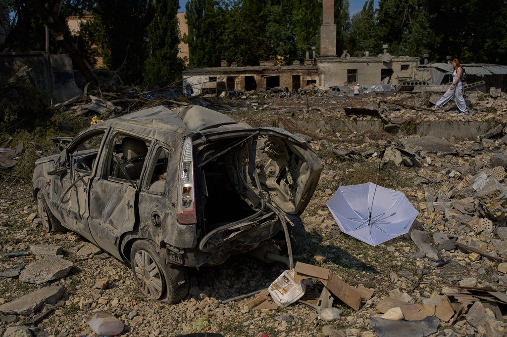 A local resident walks past destroyed vehicles and scattered debris the day after a Russian missile and drone attack in Kyiv, Friday, Aug. 21, 2026. (AP Photo/Francisco Seco)