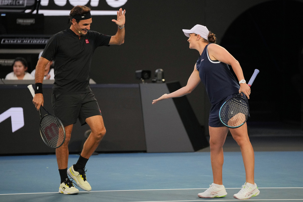 Roger Federer of Switzerland reacts with partner Ash Barty of Australia in their doubles match against Lleyton Hewitt and Pat Rafter of Australia during the Opening Ceremony for the Australian Open tennis championship in Melbourne, Australia, Saturday, Jan. 17, 2026. (AP Photo/Dita Alangkara)