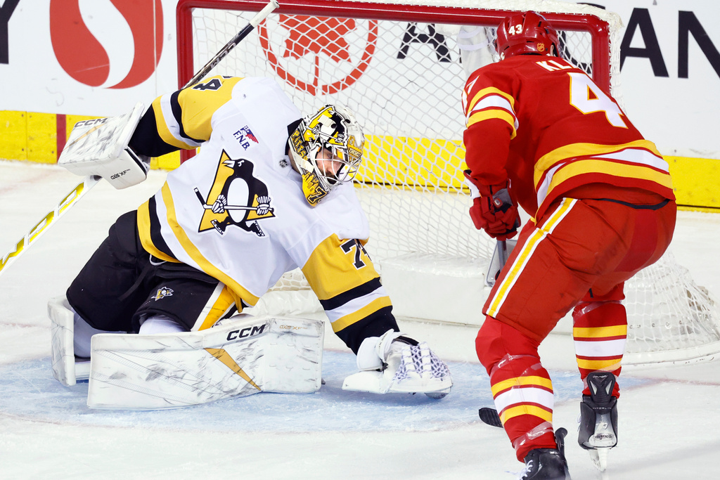 Pittsburgh Penguins goalie Stuart Skinner, left, makes a save against Calgary Flames' Adam Klapka during the second period of an NHL hockey game in Calgary, Alberta, Wednesday, Jan. 21, 2026. (Larry MacDougal/The Canadian Press via AP)