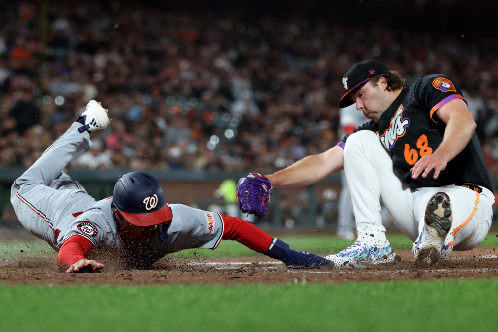 Washington Nationals' Jacob Young, left, slides home safe on a wild pitch as San Francisco Giants pitcher Erik Miller (68) applies the tag during the seventh inning of a baseball game in San Francisco, Tuesday, June 9, 2026. (AP Photo/Jed Jacobsohn)