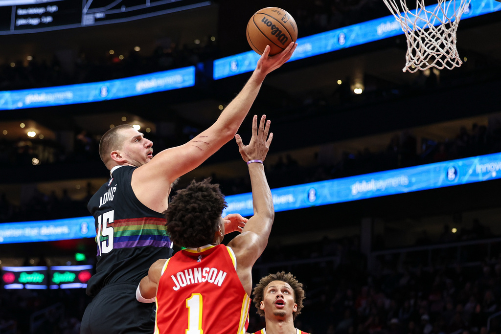 Denver Nuggets center Nikola Jokic, left, shoots the ball over Atlanta Hawks forward Jalen Johnson (1) during the first half of an NBA basketball game, Friday, Dec. 5, 2025, in Atlanta. (AP Photo/Colin Hubbard)