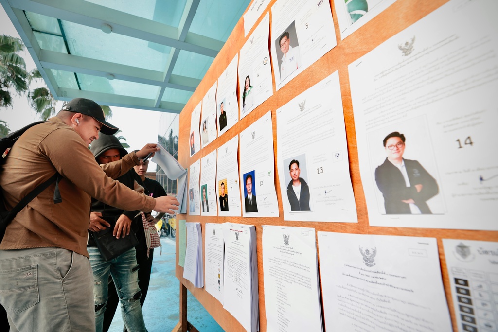 CORRECTS DATE TO 8, NOT 7 - Voters look at candidates listed on a display board before entering a voting station for the general election in Bangkok, on Sunday, Feb. 8, 2026. (AP Photo/Wason Wanichakorn)