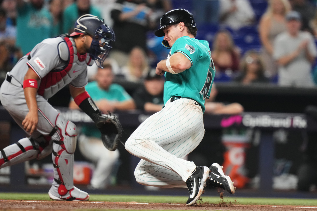 Miami Marlins' Griffin Conine, right, scores past Washington Nationals catcher Keibert Ruiz, left, on a sacrifice fly hit by Otto Lopez during the sixth inning of a baseball game, Sunday, Aug. 23, 2026, in Miami. (AP Photo/Lynne Sladky)