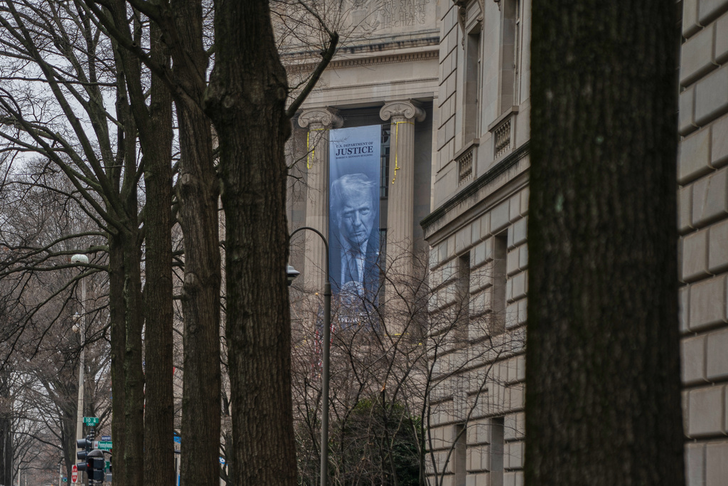 A banner showing President Donald Trump is hung from the Department of Justice, Thursday, Feb. 19, 2026, in Washington. (AP Photo/Allison Robbert)