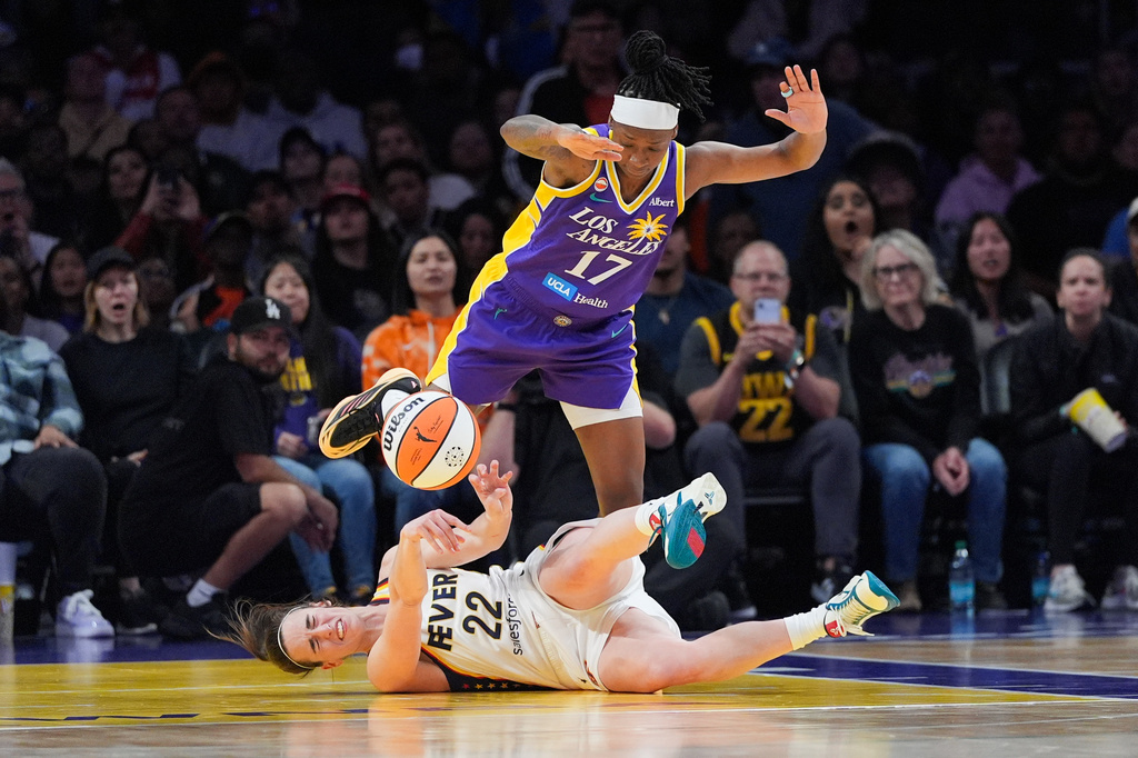Indiana Fever guard Caitlin Clark (22) attempts a pass while falling to the court as Los Angeles Sparks guard Erica Wheeler (17) defends during the second half of a WNBA basketball game Wednesday, May 13, 2026, in Los Angeles. (AP Photo/Jae C. Hong)