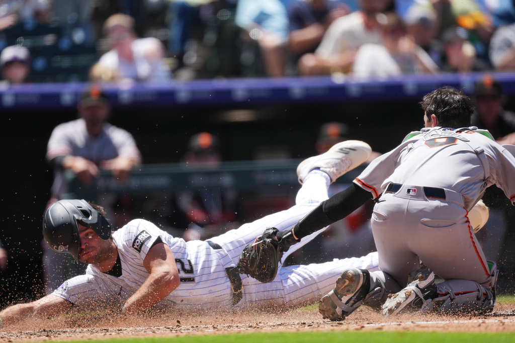 San Francisco Giants catcher Daniel Susac, right, applies a late tag as Colorado Rockies' Kyle Karros, left, scores on a sacrifice fly hit by Braxton Fulford in the second inning of a baseball game Sunday, May 31, 2026, in Denver. (AP Photo/David Zalubowski)
