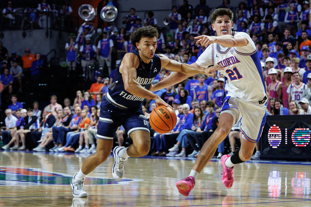 North Florida Ospreys guard Kamrin Oriol (11) drives past Florida Gators forward Alex Condon (21) during the first half of an NCAA college basketball game, Thursday, Nov. 6, 2025, in Gainesville, Fla. (AP Photo/Chris Watkins)