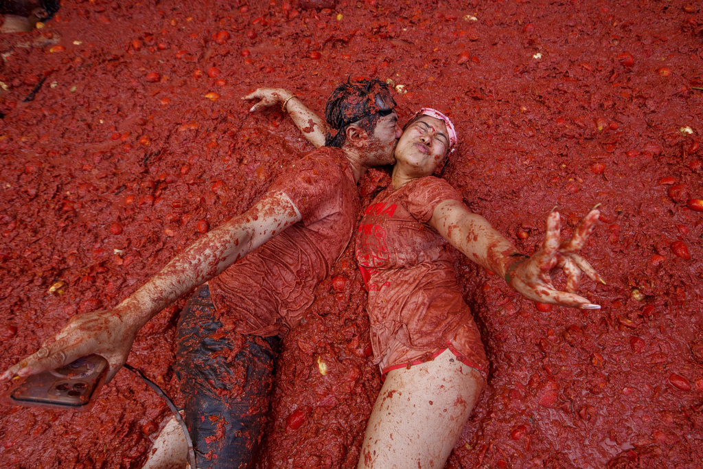 A couple kisses over a puddle of tomatoes during the annual "Tomatina" tomato fight fiesta, in the village of Bunol near Valencia, Spain, Wednesday, Aug. 27, 2025. (AP Photo/Alberto Saiz)