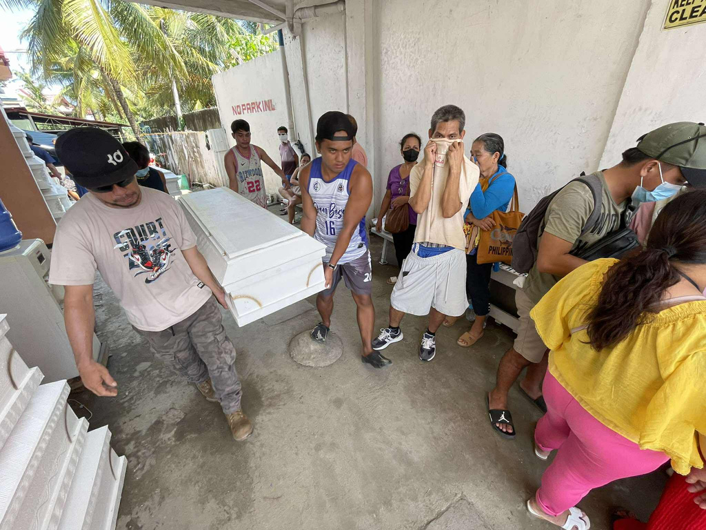 Relatives wait beside coffins of their loved ones at a funeral parlor in Liloan, Cebu province, central Philippines on Thursday Nov. 6, 2025 after residents perished as they were swept away by strong currents at the height of Typhoon Kalmaegi. (AP Photo/Jacqueline Hernandez)