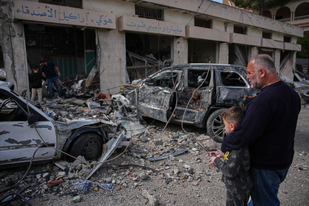 Locals residents stand among debris and vehicles destroyed in an Israeli airstrike in Jibchit, southern Lebanon, Friday, April 17, 2026, following a ceasefire between Israel and Hezbollah. (AP Photo/Hassan Ammar)