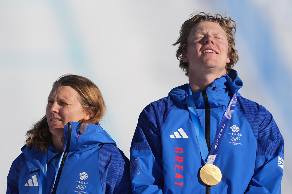 Gold medalists Britain's Charlotte Bankes and Huw Nightingale react on the podium after winning the mixed team snowboard cross finals at the 2026 Winter Olympics, in Livigno, Italy, Sunday, Feb. 15, 2026. (AP Photo/Lindsey Wasson)