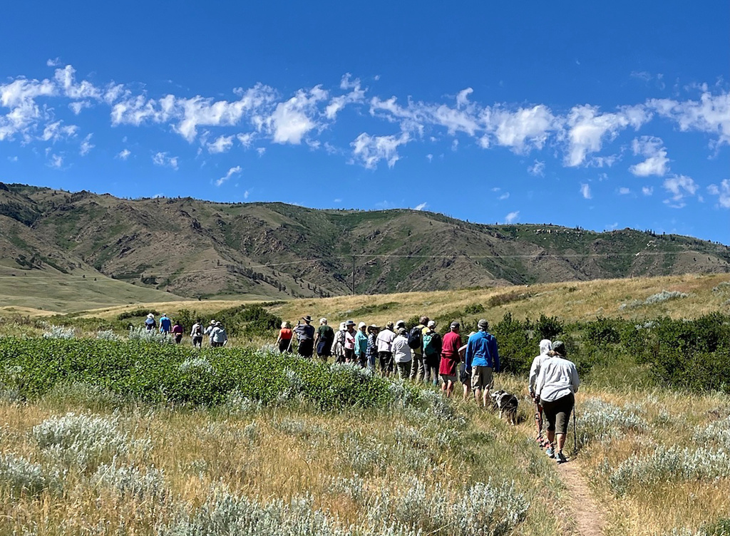 Dozens of people hike a trail June 29, 2024, on state lands west of Casper, Wyo., where Prism Logistics hopes to mine gravel. (Dustin Bleizeffer/WyoFile via AP)
