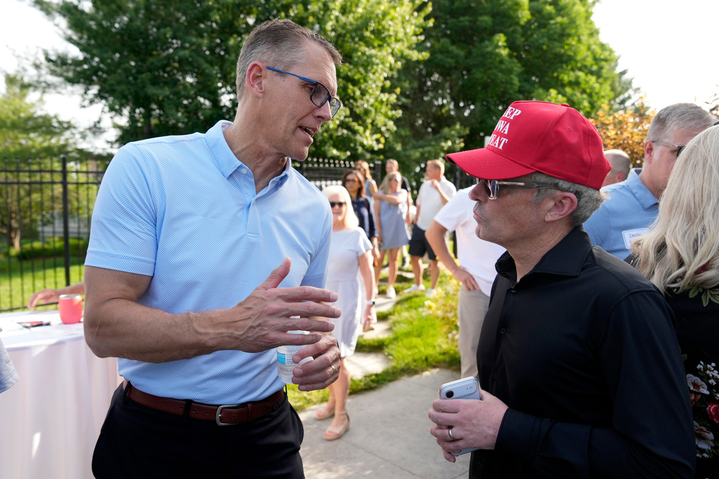 Rep. Randy Feenstra, R-Iowa, talks with Eric Branstad, right, as he campaigns for the Republican nomination for governor during a rally with local residents, Wednesday, May 27, 2026, in West Des Moines, Iowa. (AP Photo/Charlie Neibergall)