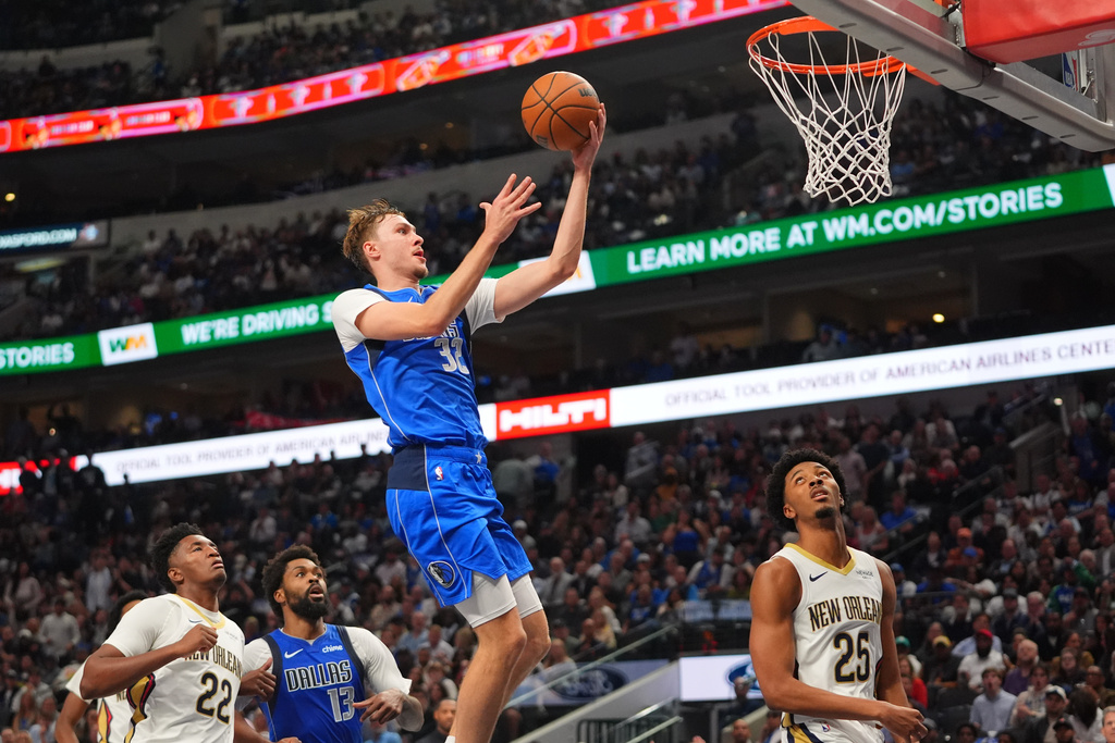 Dallas Mavericks forward Cooper Flagg (32) comes in for a layup as teammate Naji Marshall (13) looks on with New Orleans Pelicans defenders Derik Queen (22) and Trey Murphy III (25) during the first half of an NBA basketball game in Dallas, Wednesday, Nov. 5, 2025. (AP Photo/LM Otero)