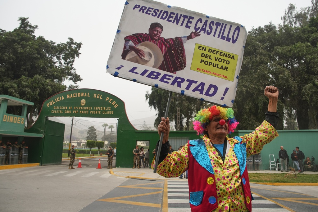 A supporter of former President Pedro Castillo, who faces charges of rebellion and other crimes against the state, holds a poster with a message that reads in Spanish: "President Castillo, freedom, in defense of the popular vote", outside the police base where Castillo attends a sentence hearing, on the outskirts of Lima, Peru, Thursday, Nov. 27, 2025. (AP Photo/Guadalupe Pardo)