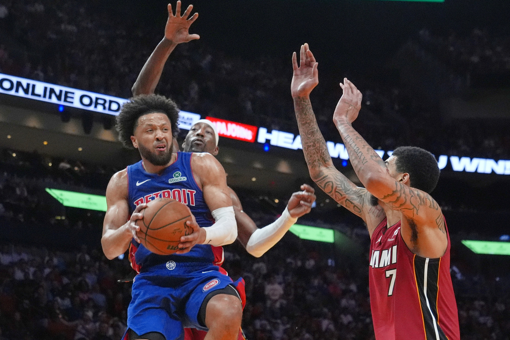 Detroit Pistons guard Cade Cunningham (2) aims to pass the ball under pressure from Miami Heat centers Kel'el Ware (7) and Bam Adebayo during the first half of an NBA basketball game Sunday, March 8, 2026, in Miami. (AP Photo/Marta Lavandier)