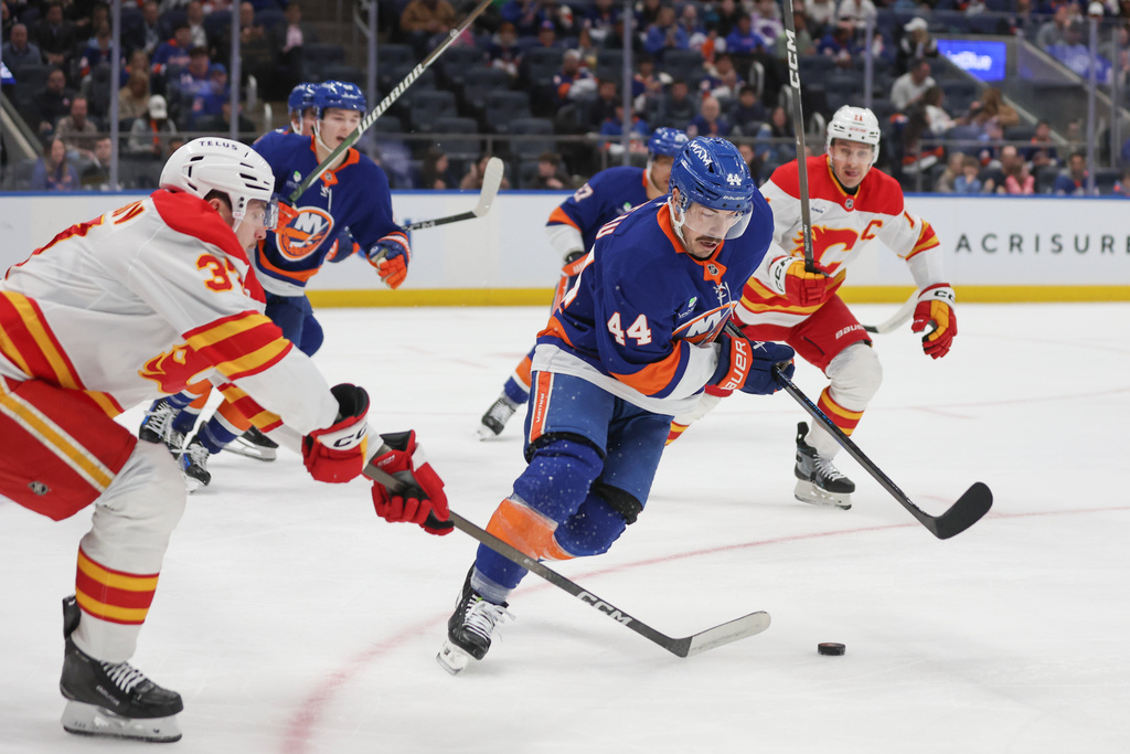 New York Islanders center Jean-Gabriel Pageau (44) takes the puck from Calgary Flames defenseman Yan Kuznetsov, left, during the first period of an NHL hockey game, Saturday, March 14, 2026, in Elmont, N.Y. (AP Photo/Heather Khalifa)