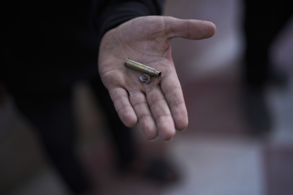 A youth holds an empty bullet cartridge and a piece of shrapnel near the spot where 12-year-old Ayman al-Heimouni was shot by Israeli gunfire in the West Bank city of Hebron, March 26, 2025. (AP Photo/Leo Correa)