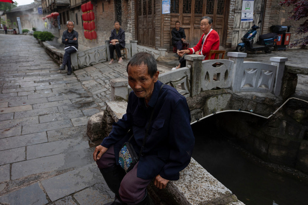 Residents rest near a stone bridge at Tianlong Tunpu, an ancient town in southwestern China's Guizhou province on Thursday, May 28, 2026. (AP Photo/Ng Han Guan)