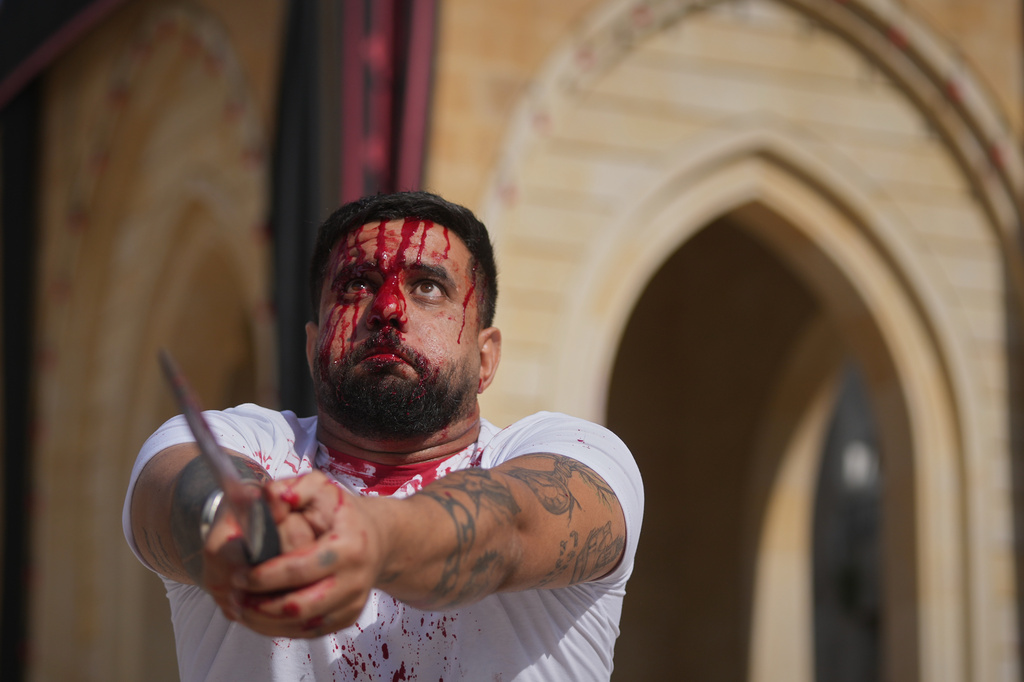 EDS NOTE: GRAPHIC CONTENT - A man bleeds from a ceremonial head wound during Ashoura, when Shiites commemorate the martyrdom of Imam Hussein, the grandson of the Prophet Muhammad, amid buildings destroyed by Israeli strikes in Nabatiyeh, southern Lebanon, Friday, June 26, 2026. (AP Photo/Hassan Ammar)