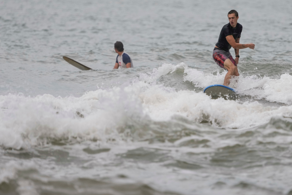Surfers try to catch a wave in surf stirred up by Tropical Storm Edouard in Galveston, Texas, Tuesday, Sept. 1, 2026. (Brett Coomer/Houston Chronicle via AP)