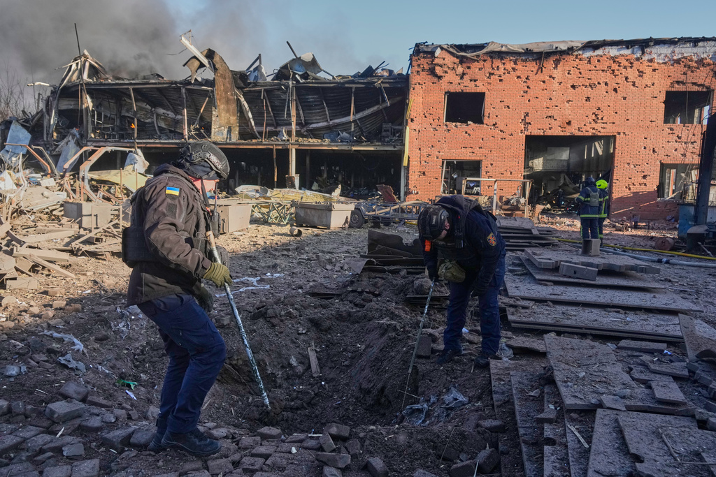 Sappers examine a drone crater at railway workshops following a Russia missile and drone attack, in Brovary close to Kyiv, Ukraine, Saturday, March 14, 2026. (AP Photo/Efrem Lukatsky)
