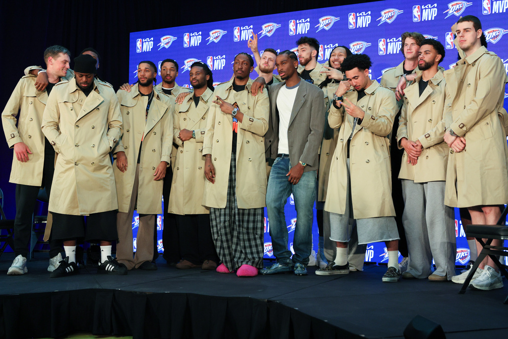 Oklahoma City Thunder guard Shai Gilgeous-Alexander, center, poses with teammates in Burberry trench coats he bought during a news conference after he was named the NBA basketball MVP, Sunday, May 17, 2026, in Oklahoma City. (AP Photo/Nate Billings)