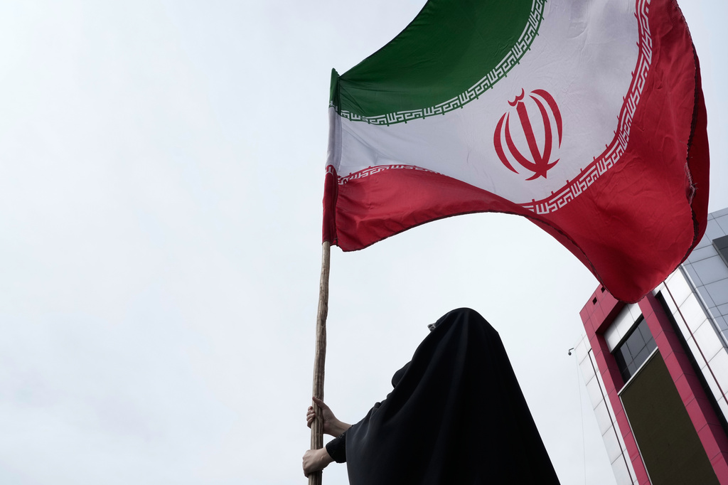 A woman holds an Iranian flag for a pro-government campaign in downtown Tehran, Iran, Saturday, April 25, 2026. (AP Photo/Vahid Salemi)