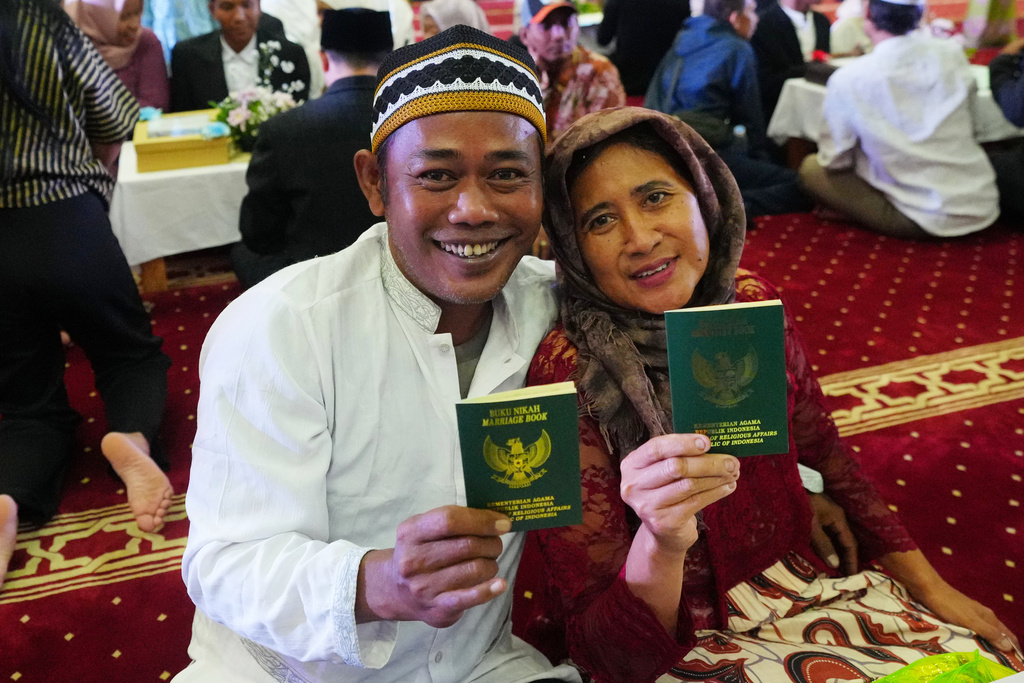 Suryadi, left, who uses only one name, and his bride Laili Nofiana show their wedding certificates after getting married in a mass wedding ceremony at Istiqlal Mosque in Jakarta, Indonesia, Wednesday, Dec. 3, 2025. (AP Photo/Tatan Syuflana)