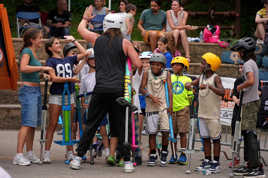 Extreme pogo athlete Harry White of Ontario, Canada, greets young neighborhood children following the conclusion of competition at Pogopalooza 2026 in Wilkinsburg, Pa., Sunday, June 14, 2026. (AP Photo/Gene J. Puskar)