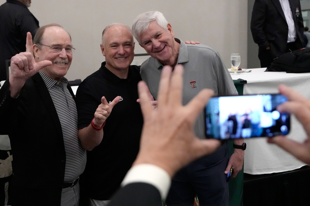 Texas Tech football coach Joey McGuire, center, poses for photographs after speaking during The Houston Touchdown Club luncheon, Wednesday, June 10, 2026, in Houston. (AP Photo/David J. Phillip)