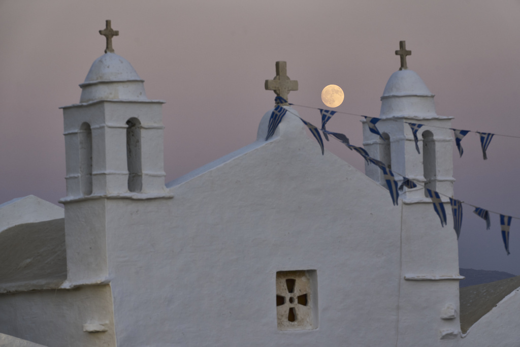 The moon rises behind the family-owned Agios Sostis chapel during its panigiri day on the island of Tinos, Greece, Saturday, Sept. 6, 2025. (AP Photo/Petros Giannakouris)