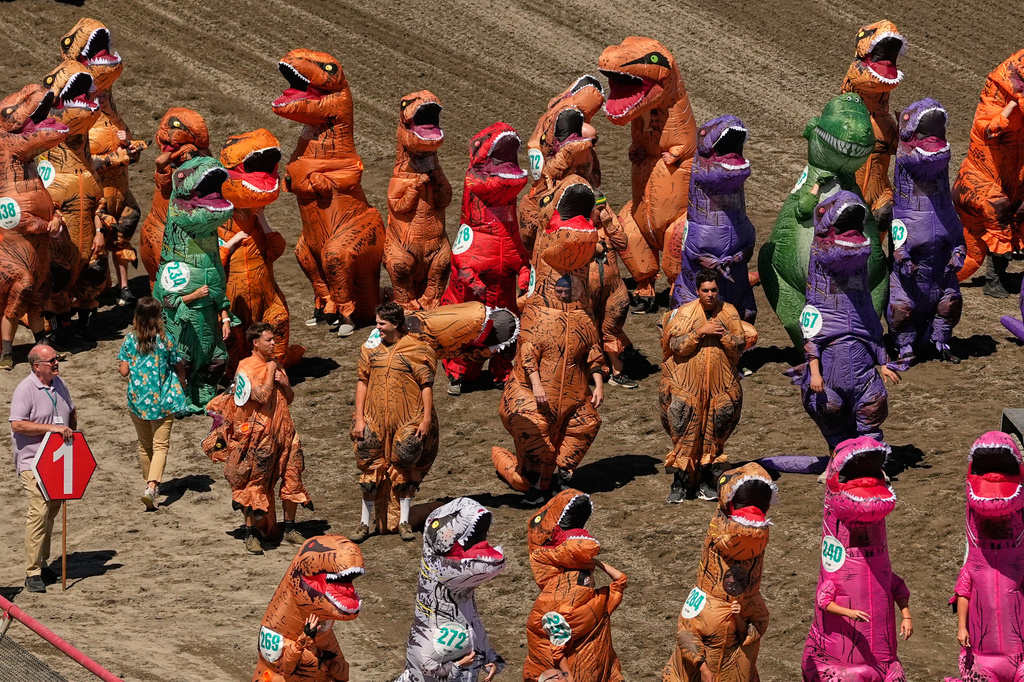 Racers in inflatable T. rex costumes wait to participate in the during the T-Rex World Championship Races at Emerald Downs, Sunday, July 12, 2026, in Auburn, Wash. (AP Photo/Lindsey Wasson)