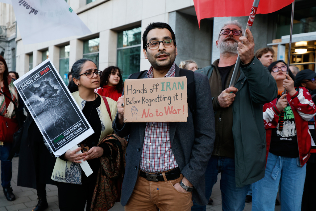 A group of people hold signs during a demonstration in reaction to the U.S. and Israeli strikes on Iran, in Brussels, Monday, March 2, 2026. (AP Photo/Geert Vanden Wijngaert)