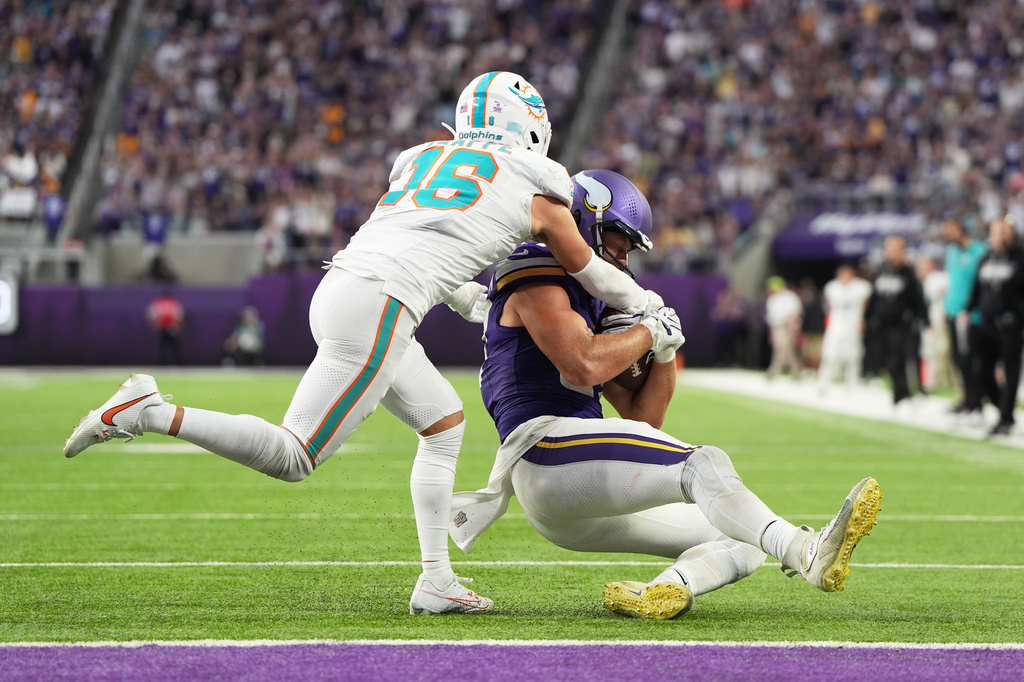 Minnesota Vikings tight end T.J. Hockenson, right, slides to down the ball as Miami Dolphins safety Michael Taaffe (16) tries to stop him during the second half of an NFL football game Sunday, Oct. 4, 2026, in Minneapolis. (AP Photo/Abbie Parr)